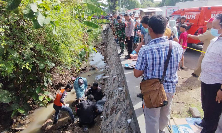 SEBELUM DIEVAKUASI: Petugas kepolisian berada di parit tepi jalan Wonorejo, tempat korban ditemukan.