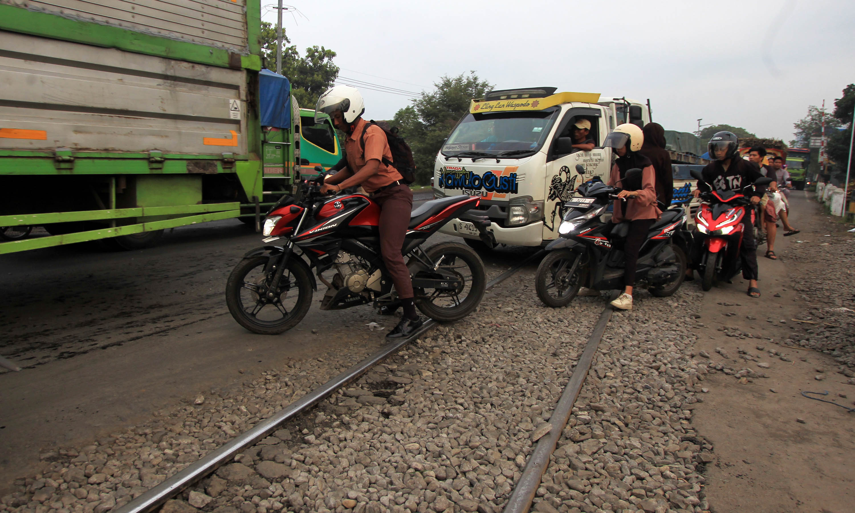 HATI-HATI: Pengendara mengatur roda motornya agar tidak selip saat melintas di perlintasan KA di Curahtulis, Tongas.