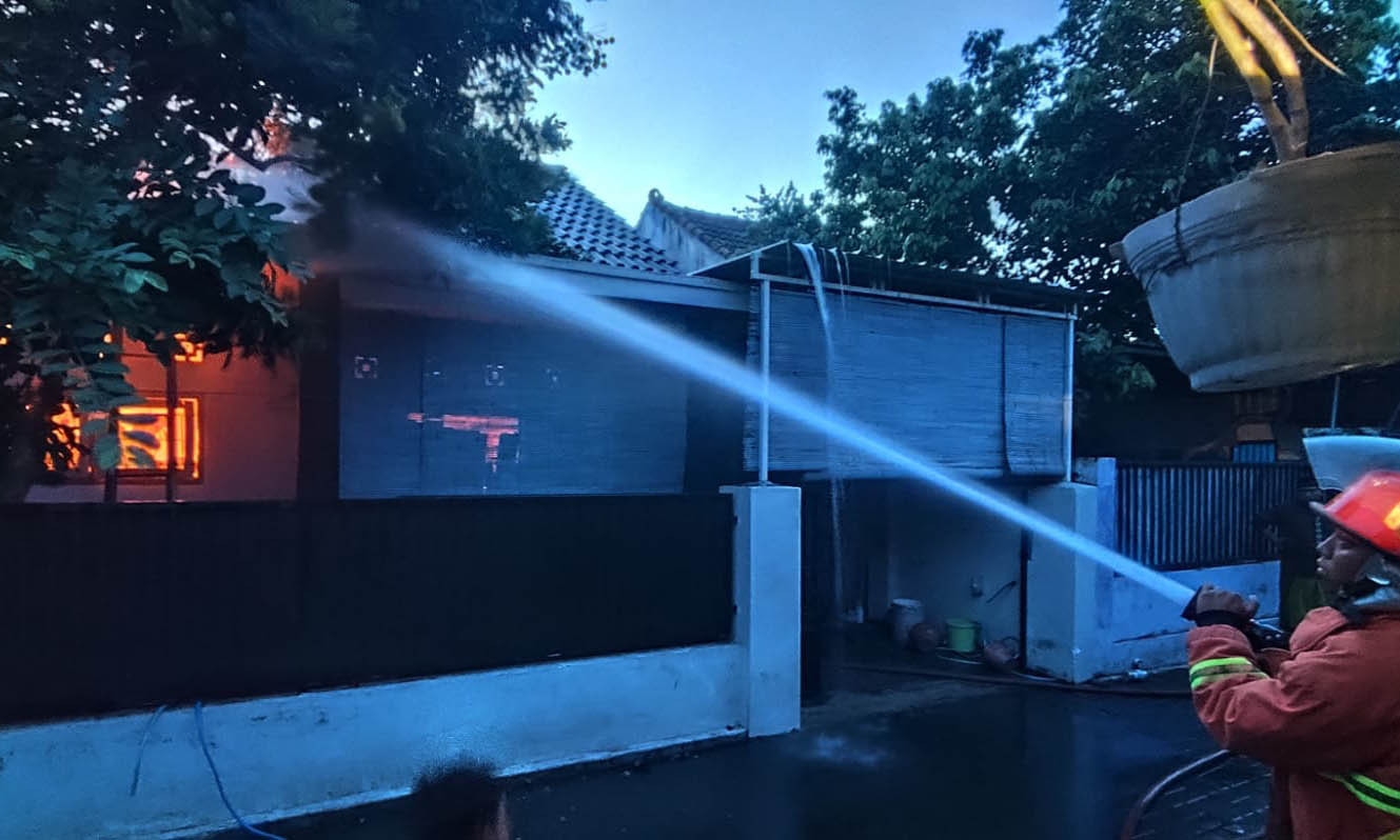 SIRAM: Personel damkar memadamkan api yang membakar rumah Khusni Mubarok dan Anita di Desa Kersikan, Selasa (16/12) pagi.