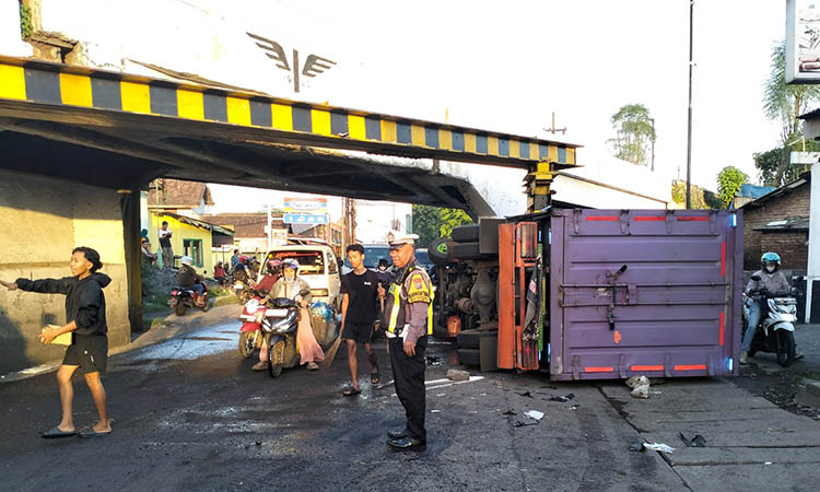 TERGULING: Truk boks pengangkut pakan yang terguling usai menabrak pembatas viaduk. Ironisnya, saat bersamaan ada pemotor yang kemudian tertimpa.