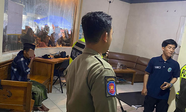 SEMPAT DIAMANKAN: Terduga pelaku berpeci hitam (duduk kiri) yang diamankan petugas di pos pengamanan Alun-alun Pasuruan, ditonton banyak pengunjung.