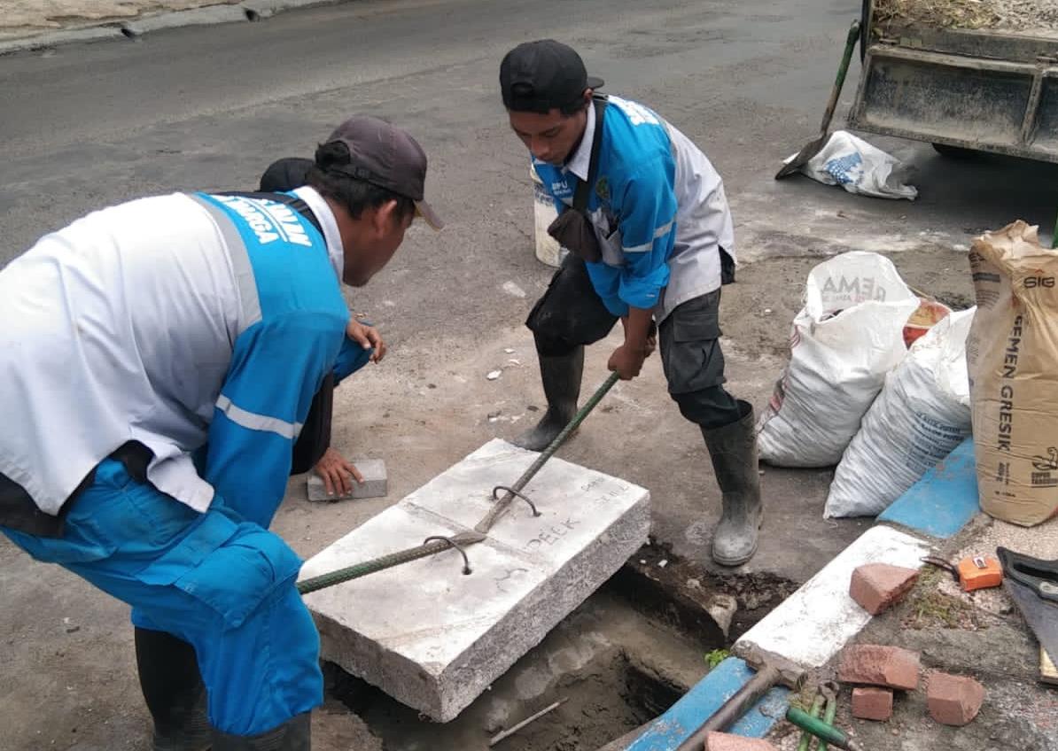 KELILING: Dua anggota Satgas Jalan dan Jembatan Dinas PUPR Kota Pasuruan sedang melakukan pemeliharaan jalan. Tiap hari mereka keliling selama Nataru.