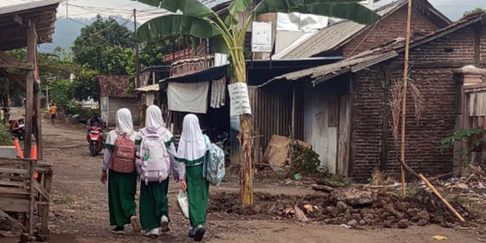 PROTES: Sejumlah pelajar melintas di Jalan Triwungan-Gondosuli, Kecamatan Pakuniran, yang ditanami pohon pisang karena rusak.