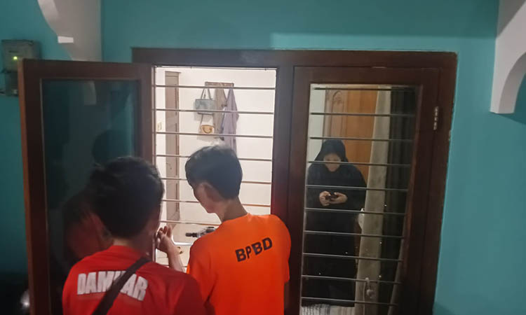 TERKUNCI: Personel damkar saat membuka pintu di rumah warga Perum Puri Candi yang terkunci di dalam kamar,