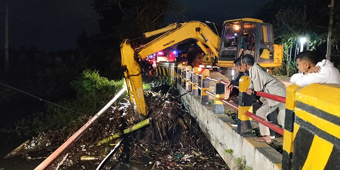 MENUMPUK: Pekerja menggunakan ekskavator mengangkat tumpukan sampah bawaan banjir yang menyumbat saluran jembatan avour Glintongan, Desa Brumbungan Lor, Kecamatan Gending.