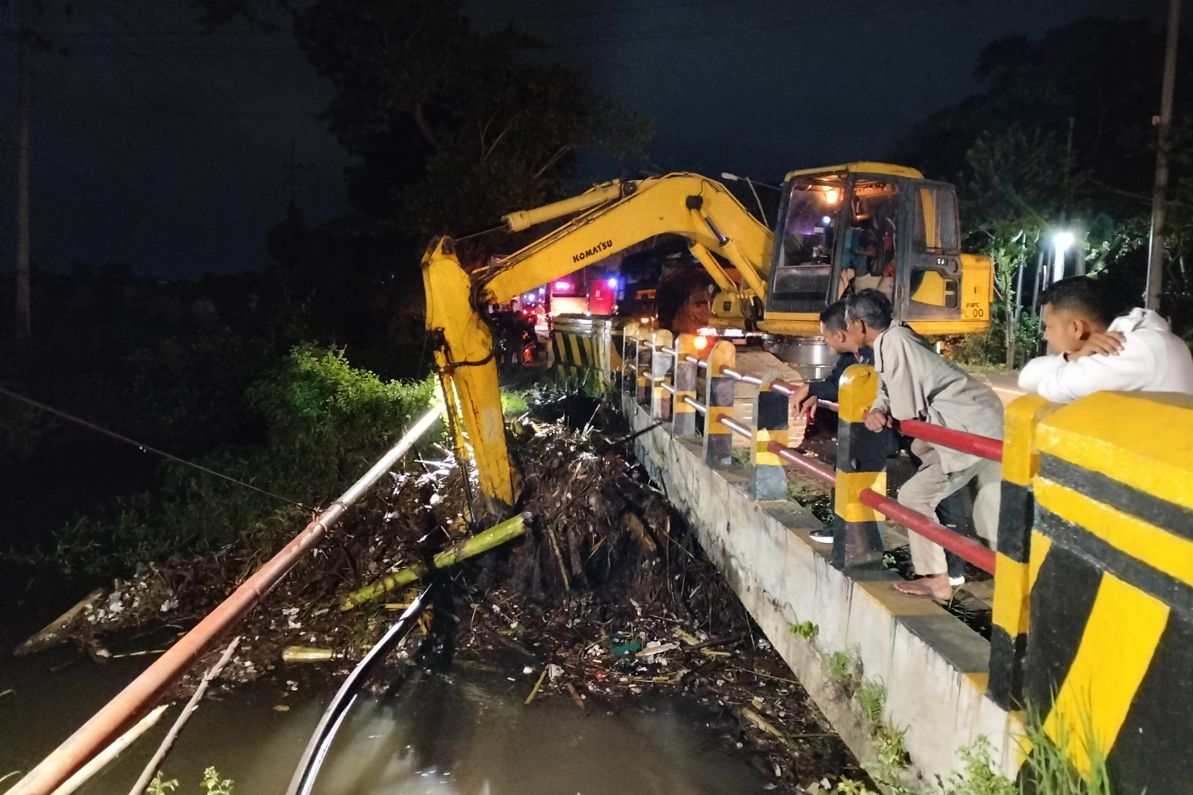 MENUMPUK: Pekerja menggunakan ekskavator mengangkat tumpukan sampah bawaan banjir yang menyumbat saluran jembatan avour Glintongan, Desa Brumbungan Lor, Kecamatan Gending.