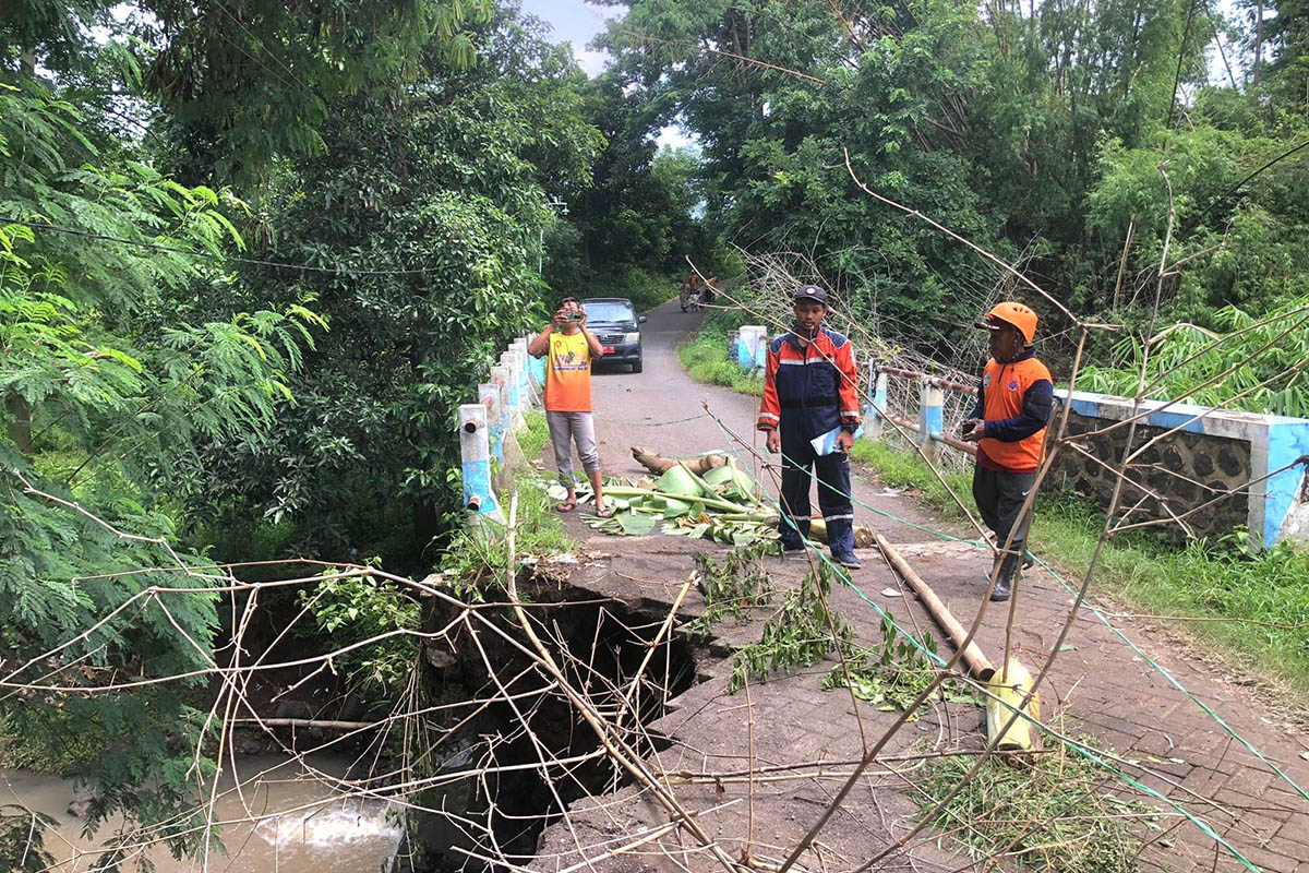 ASESMEN: Petugas BPBD Kabupaten Pasuruan saat melakukan pengecekan terhadap TPT jembatan yang ambrol. Kondisi itu, membahayakan pengguna jalan.