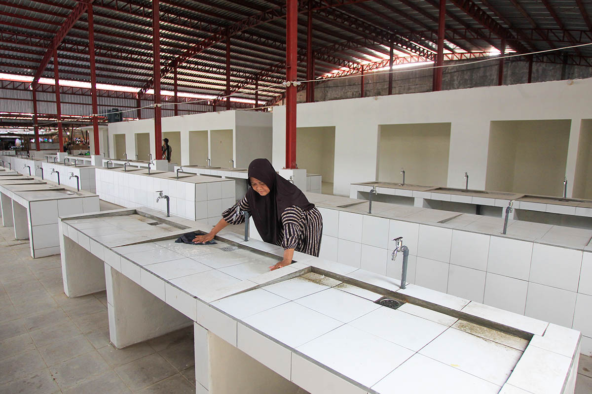 BERSIHKAN: Seorang pedagang Pasar Besar saat membersihkan stan daging. Meski kios dan stan yang dibangun telah rampung, namun belum bisa difungsikan.