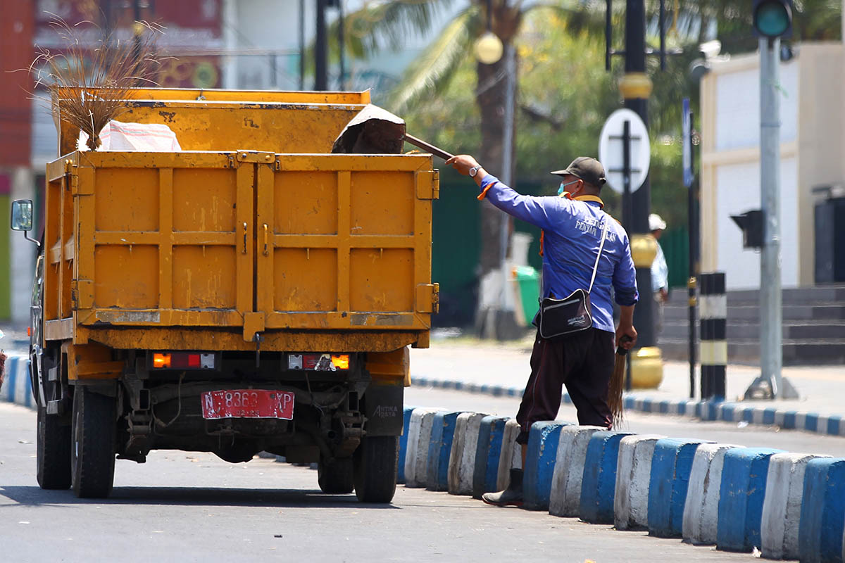 ANGKUT: Seorang petugas kebersihan Kota Pasuruan saat mengangkut dan menaruh sampah di armada pengangkut sampah. Produksi sampah di Kota Pasuruan saat ini, cenderung stagnan.