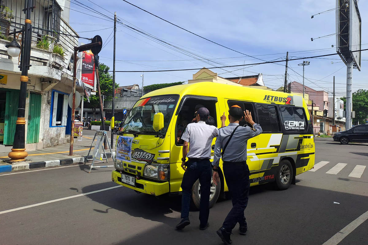 DILARANG: Petugas saat menghalau minibus yang hendak masuk pusat Kota Pasuruan. Mereka mengarahkan, agar sopir bus parkir di Kawasan Parkir Wisata.