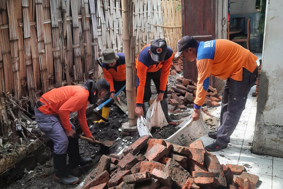BANTU: Personel BPBD memlihat batu bata yang terlepas dari bangunan rumah warga. Bata itu dipilah karena ada yang bisa dipakai lagi.