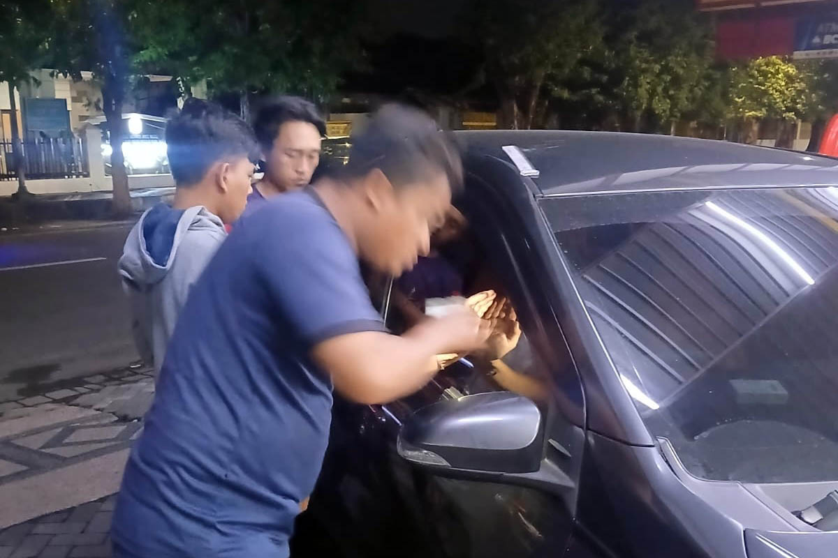 TERKUNCI: Petugas saat berusaha mengambil kunci mobil yang tertinggal di dalam kendaraan.
