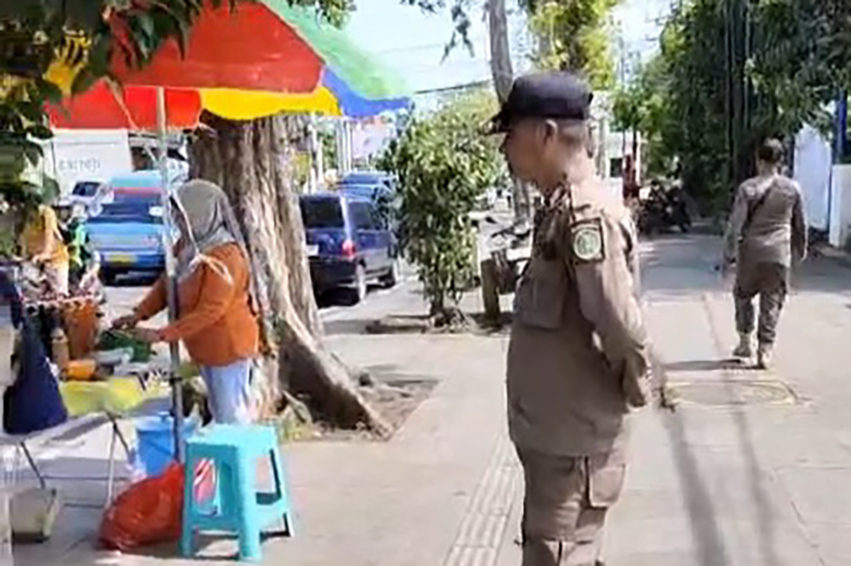 DITERTIBKAN: Seorang anggota Satpol PP Kota Pasuruan menegur PKL yang berjualan di Jalan dr. Wahidin Kota Pasuruan, Minggu (25/1).
