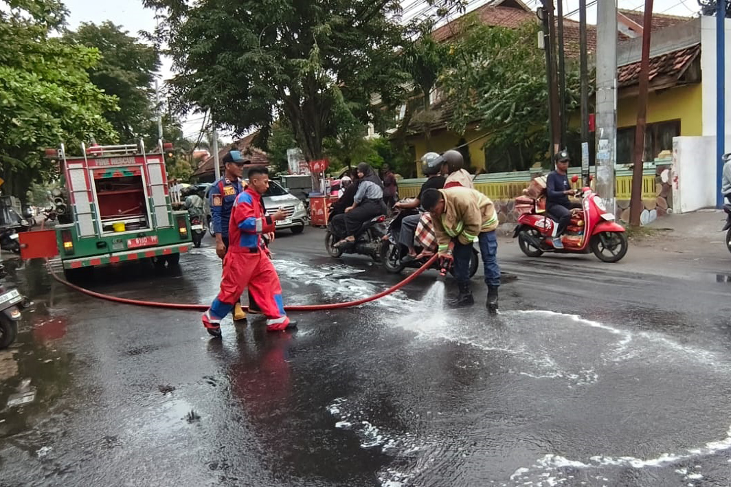 SIRAM: Tim Damkar Satpol PP Kota Probolinggo membersihkan tumpahan solar di Jalan HOS Cokroaminoto, Kota Probolinggo, Senin (26/1).