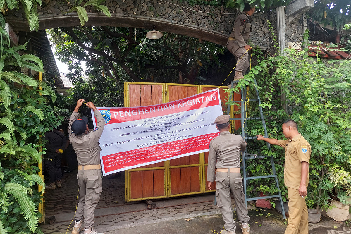 Petugas Satpol PP saat memasang banner penutupan dan pencabutan izin homestay Hadi