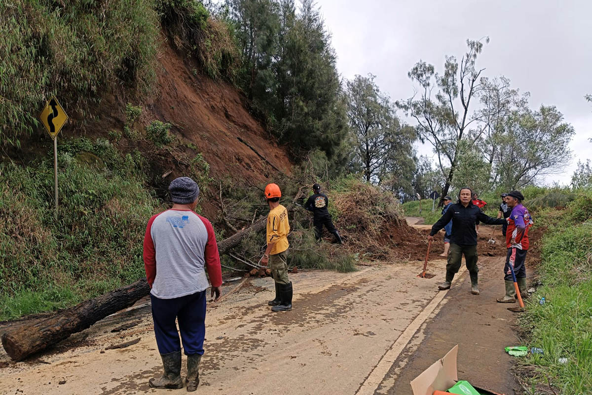 BERSIHKAN: Tim gabungan saat melakukan pembersihan jalan dari material longsor. Kondisi material yang menutup jalan itu, sempat membuat arus tersendat.