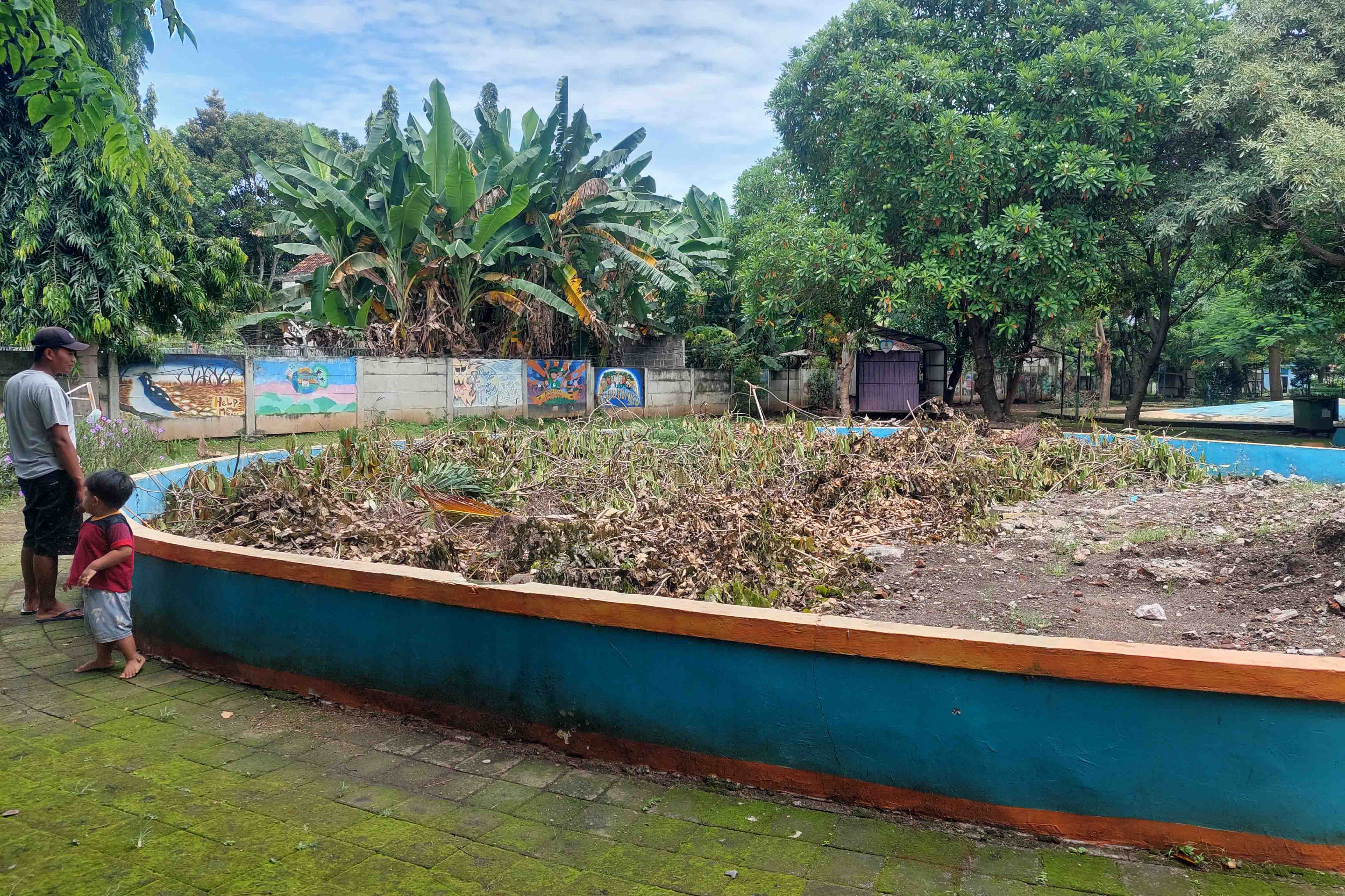 TAK TERURUS: Seorang warga memperhatikan kolam di Taman Maramis, Kota Probolinggo, yang diuruk.