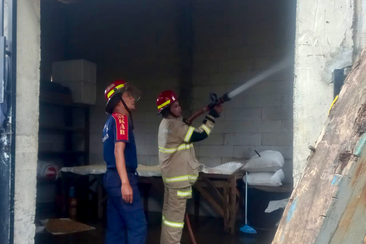 PENDINGINAN: Tim Damkar Pos Unit Dringu melakukan pendinginan tempat produksi tahu yang terbakar di Desa Kalirejo, Kecamatan Dringu.