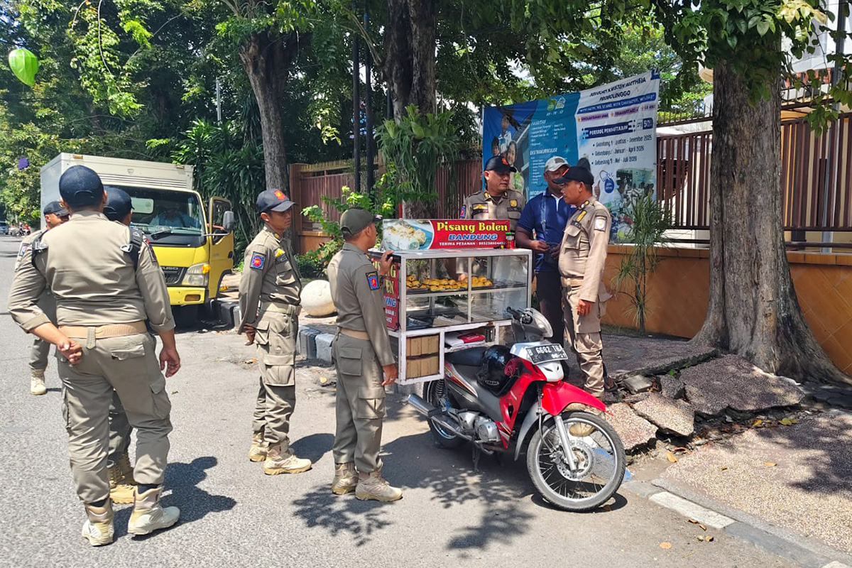 PENERTIBAN: Anggota Satpol PP Kota Probolinggo menertibkan seorang PKL di Jalan Suroyo, Kota Probolinggo.
