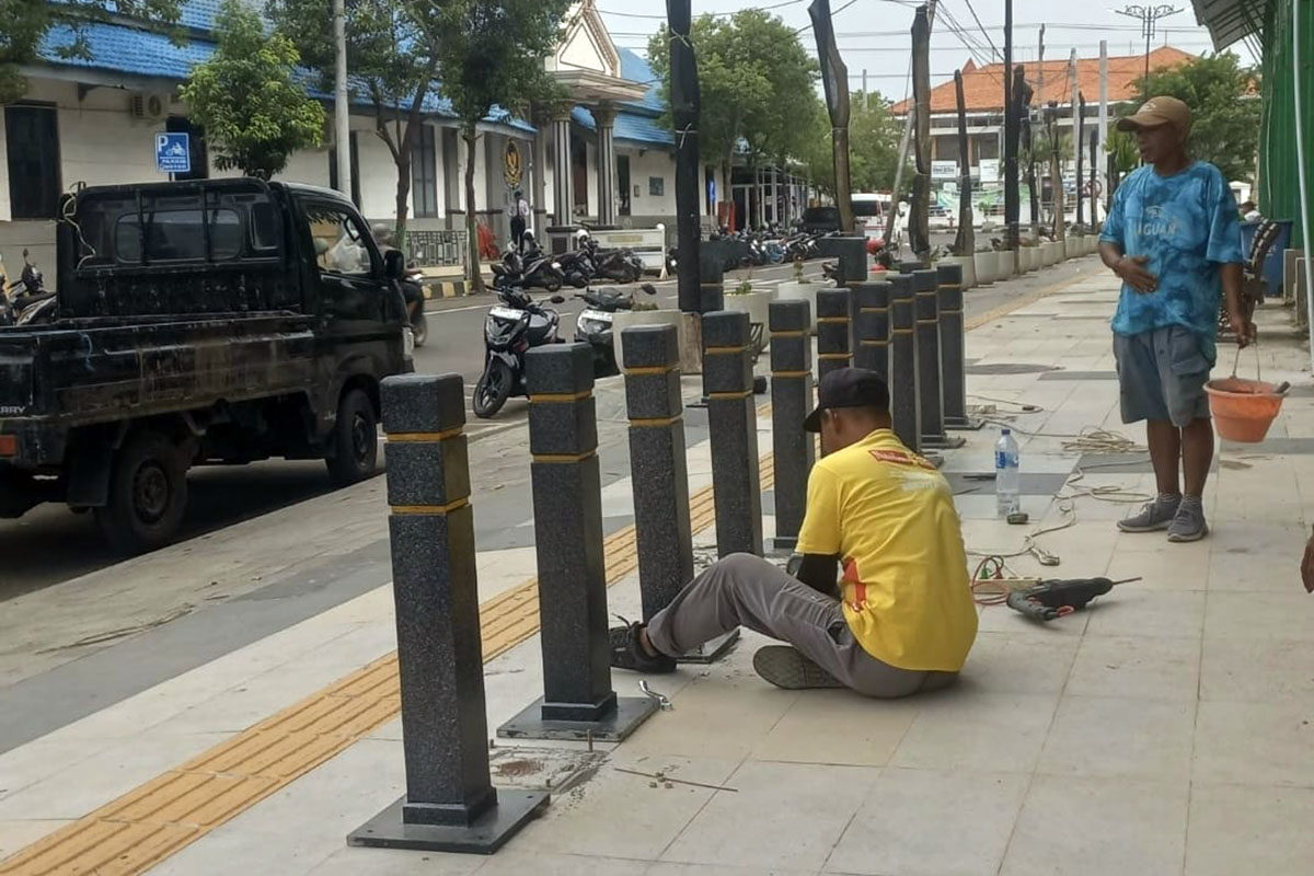 LANGSUNG DIPERBAIKI: Petugas memperbaiki bollard di sisi timur Alun-alun Probolinggo yang mulai goyang. (Arif Mashudi/ Radar Bromo)