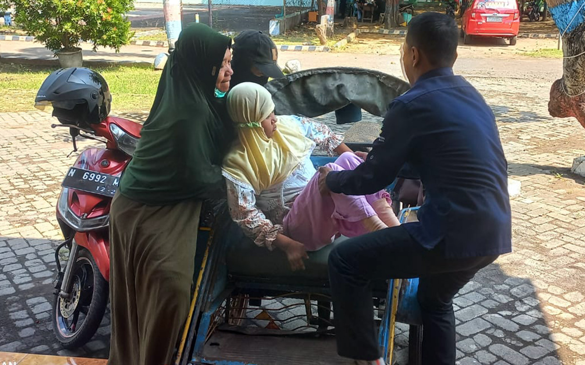 MEMBANTU: Maidi membantu disabilitas memfasilitasi pembuatan KTP di Kecamatan Kraksaan beberapa waktu lalu.