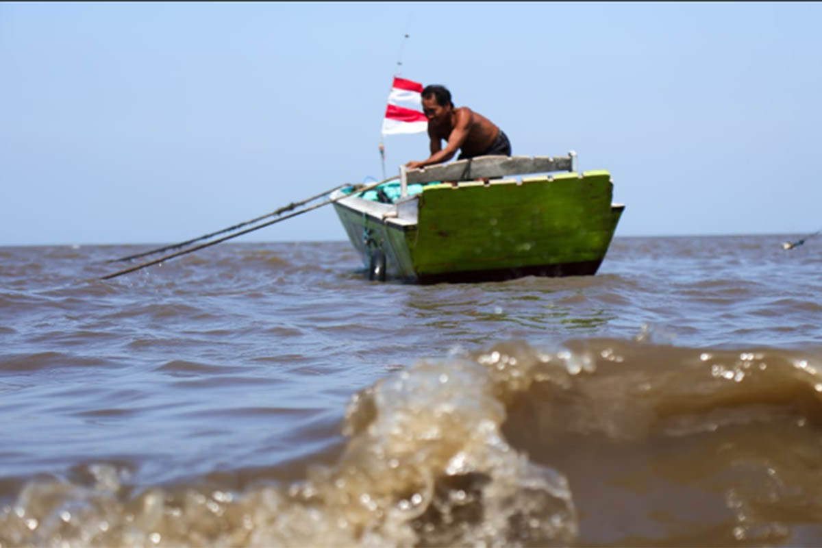 HARUS HATI-HATI: Nelayan di pesisir Lekok, Kabupaten Pasuruan merawat perahunya lantaran libur melaut akibat ombak tinggi.
