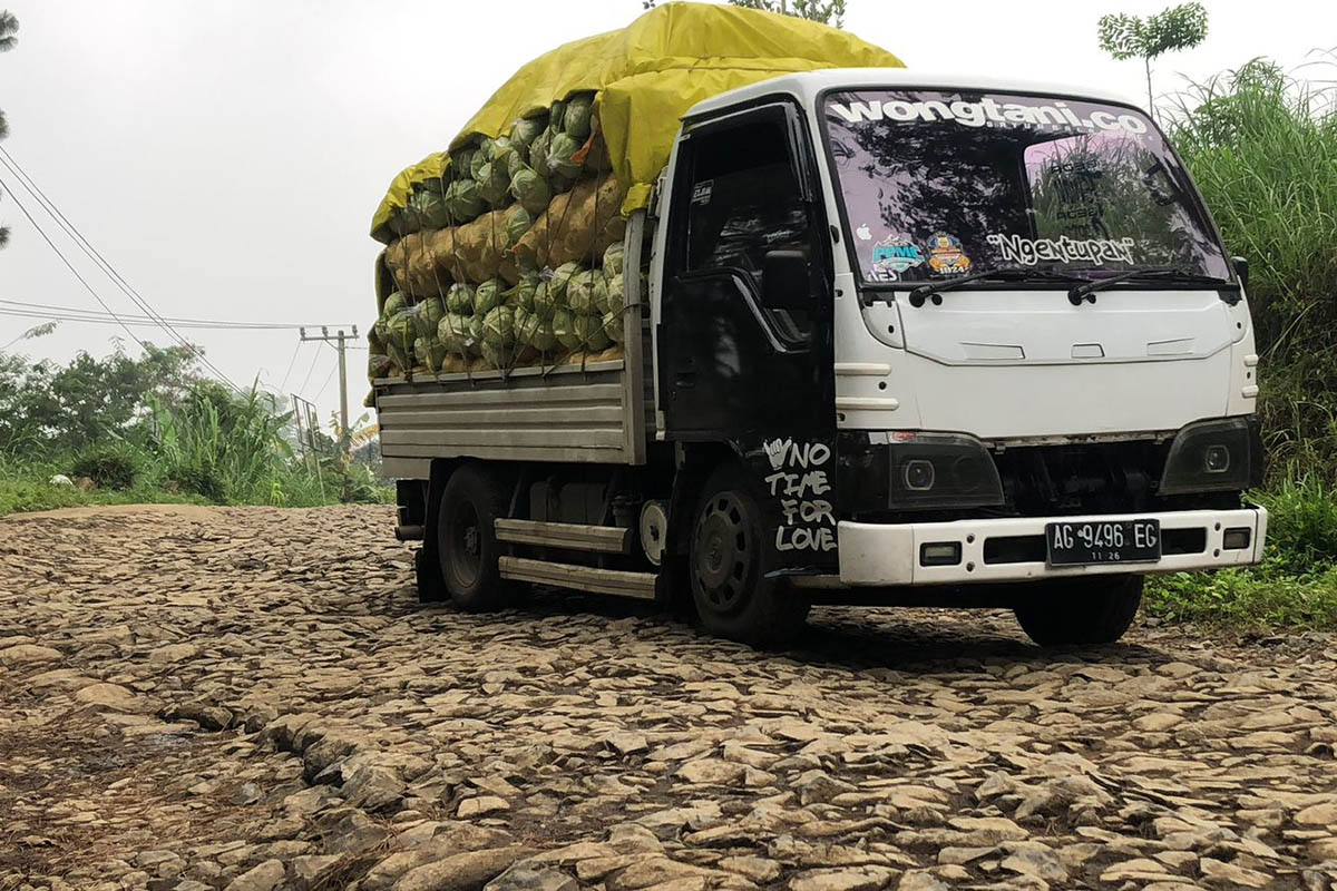 GANGGU AKSES: Kendaraan memuat hasil pertanian melintas di jalan yang rusak di wilayah Kecamatan Sumber. Pemkab Probolinggo sudah merencanakan perbaikan di jalan ini.