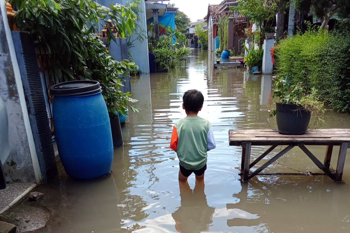 Seorang bocah melintasi jalanan perkampungannya yang terendam banjir. (Rizal Syatori/ Radar Bromo)