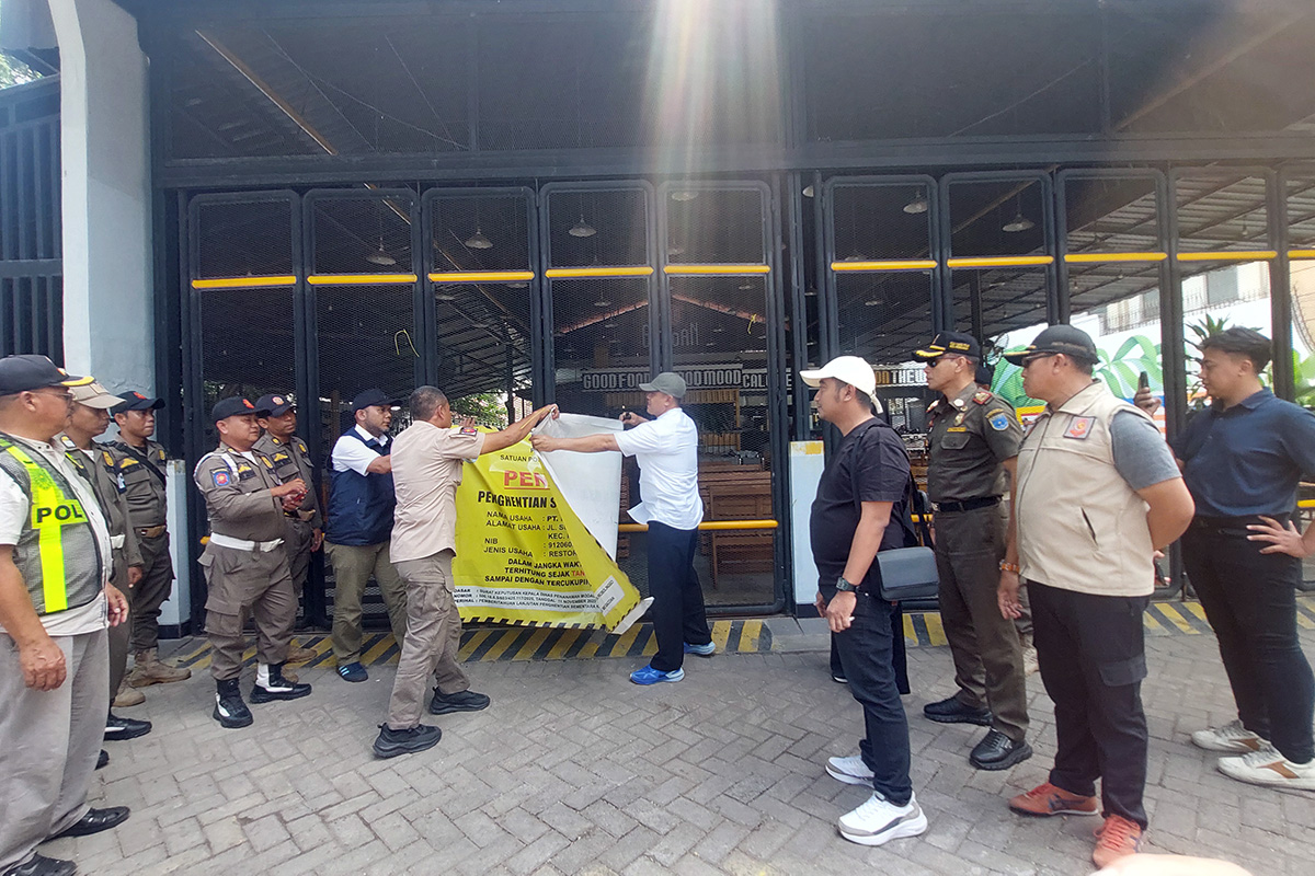 SEGEL DILEPAS: Petugas Satpol PP Pemkot Probolinggo saat mencopot segel penutupan Mie Gacoan Probolinggo, Jumat (6/2). (Arif Mashudi/ Radar Bromo)