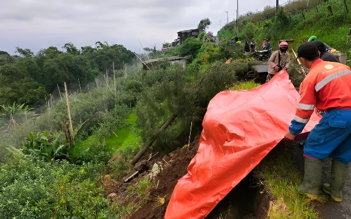 DITUTUP TERPAL: BPBD Kabupaten Pasuruan saat memasang terpal untuk menandai dan menutupi jalan yang ambles. Dampak amblesnya  jalan tersebut, akses di Tutur tersendat. Terutama untuk roda empat.