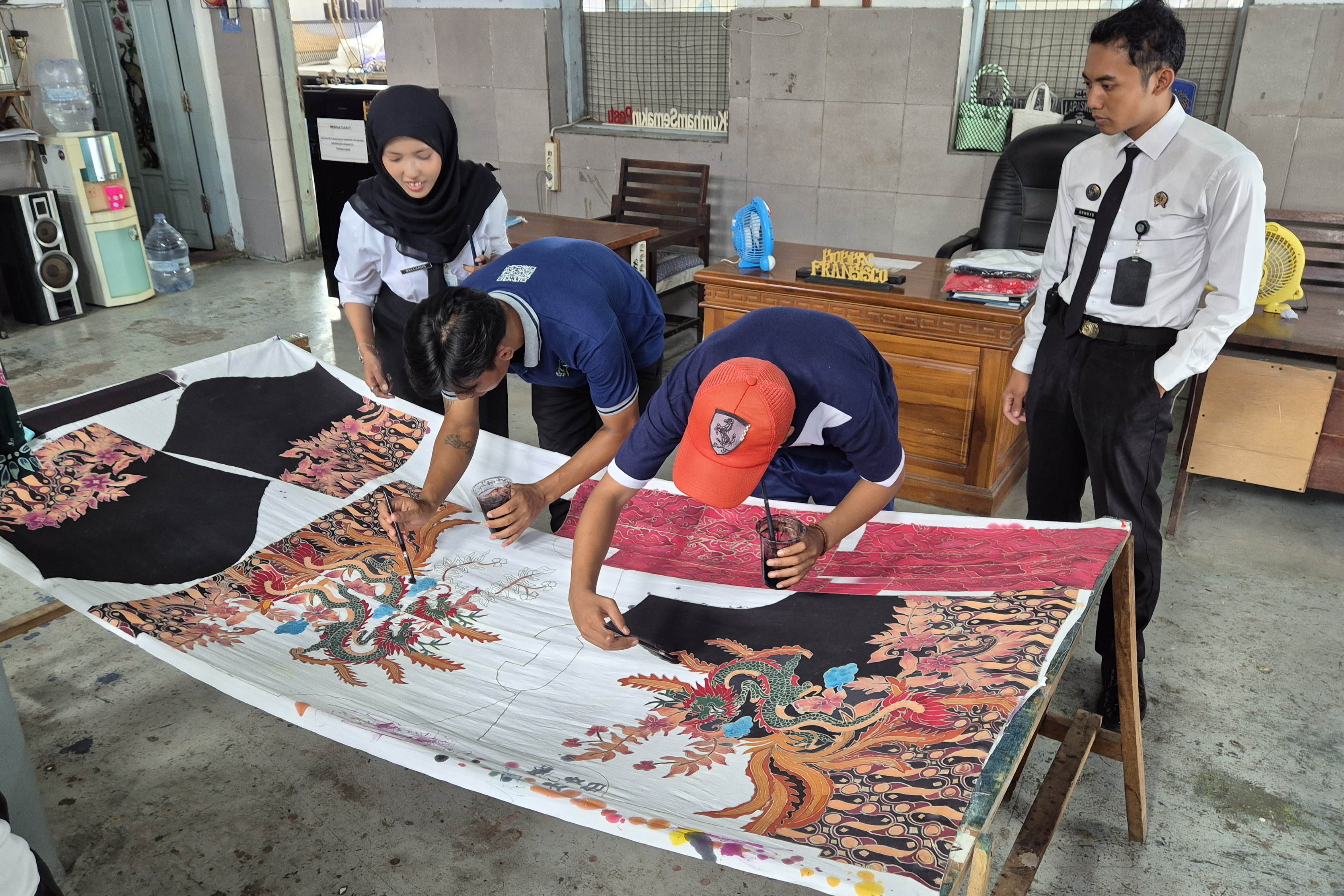 JADI BEKAL: Warga binaan di Lapas Pasuruan melakukan pewarnaan pada batik tulis dipantau oleh Nabila Ans yang sedang magang.