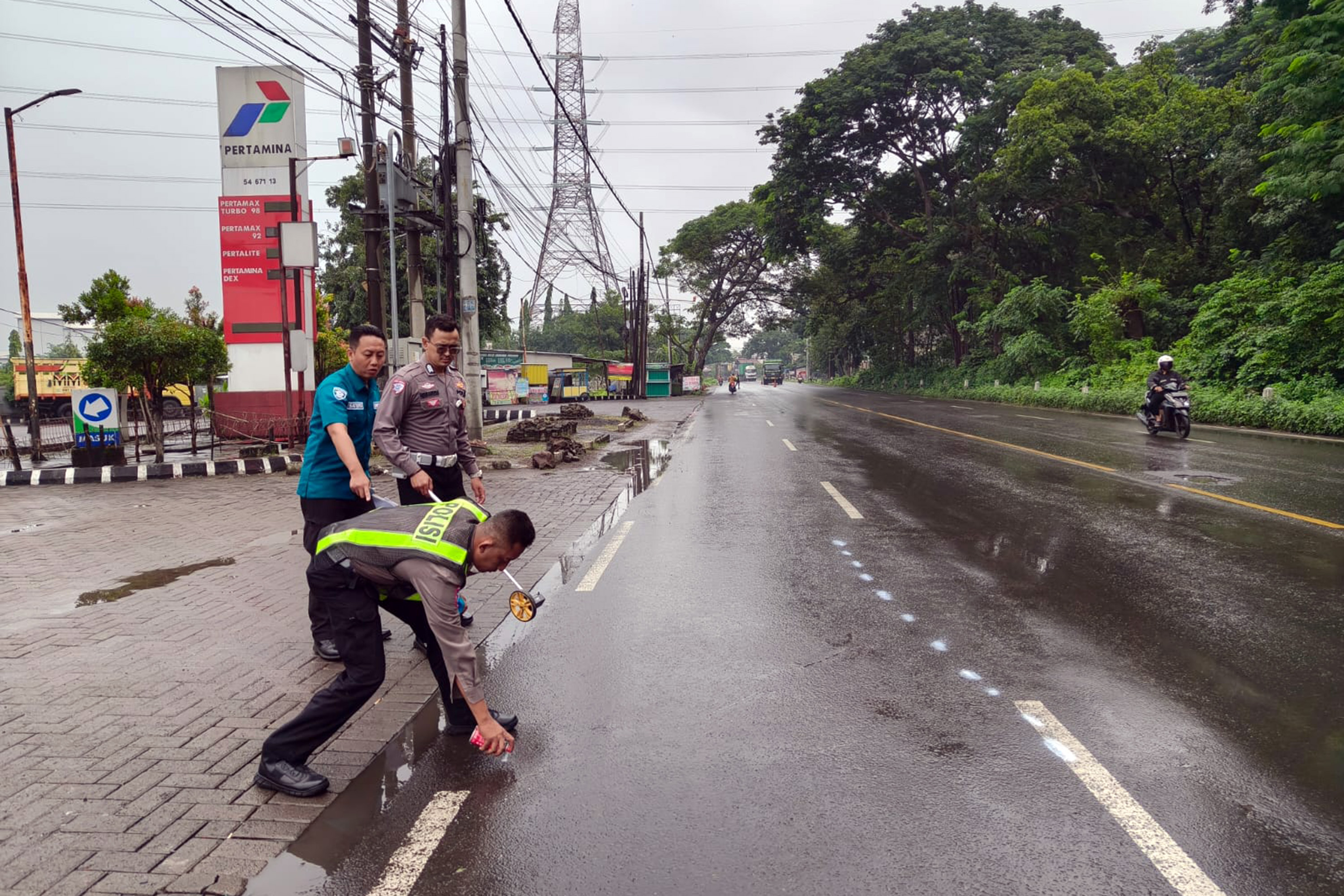 NAHAS: Petugas kepolisian saat melakukan olah TKP insiden kecelakaan yang menewaskan pemotor. (Istimewa)