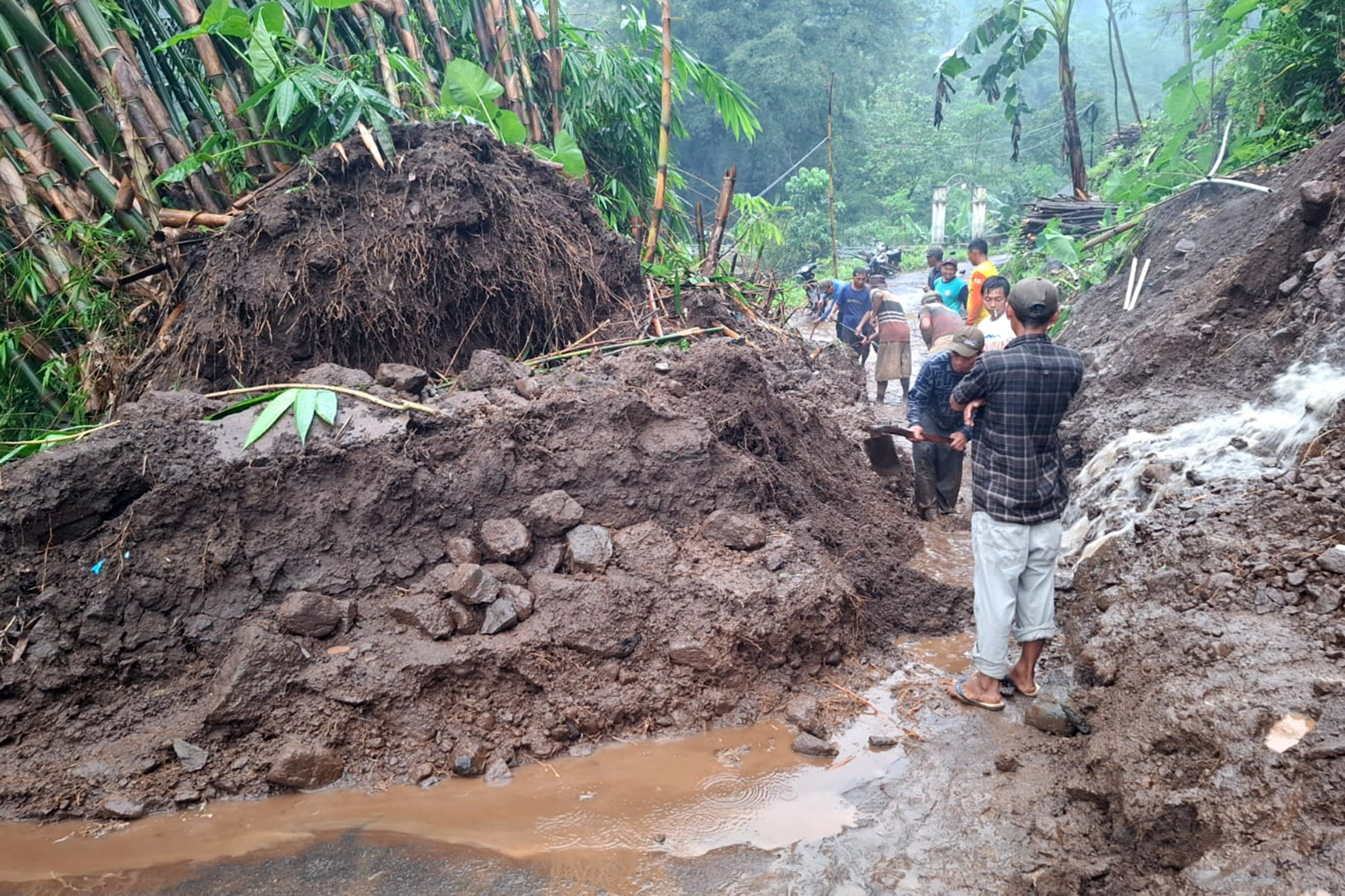 Sejumlah warga Welulang, Lumbang, Kabupaten Pasuruan saat berupaya mengevakuasi material longsor yang menutup jalan, Senin sore (9/2). (Istimewa)