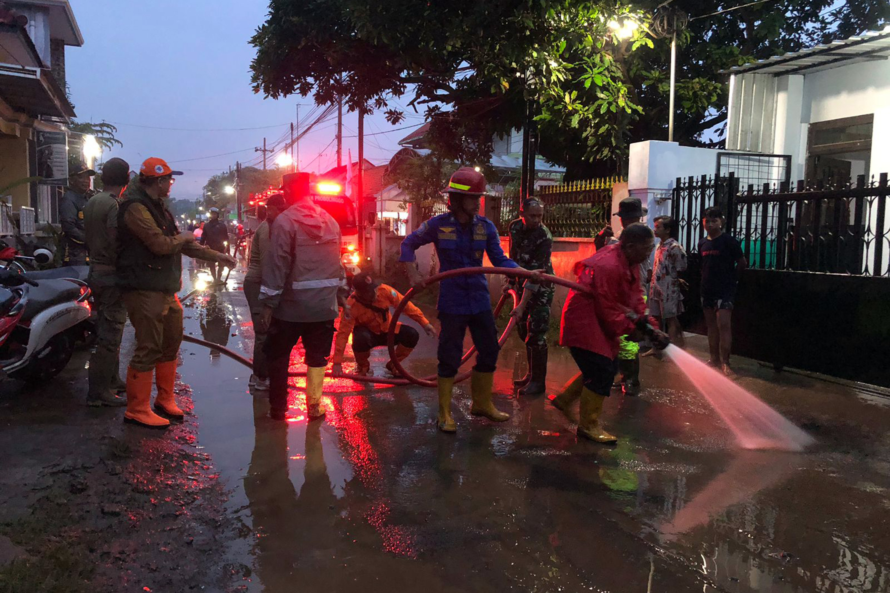 Petugas damkar menyemprot jalan Daendles di Dringu Probolinggo usai terendam banjir, Senin petang (10/2).