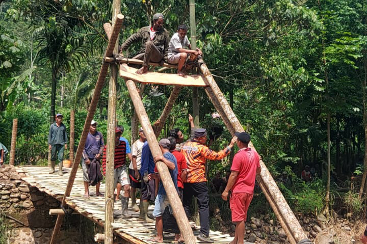 DIBANGUN: Sejumlah warga membangun jembatan darurat di Kecamatan Tiris setelah jembatan sebelumnya rusak diterjang banjir.