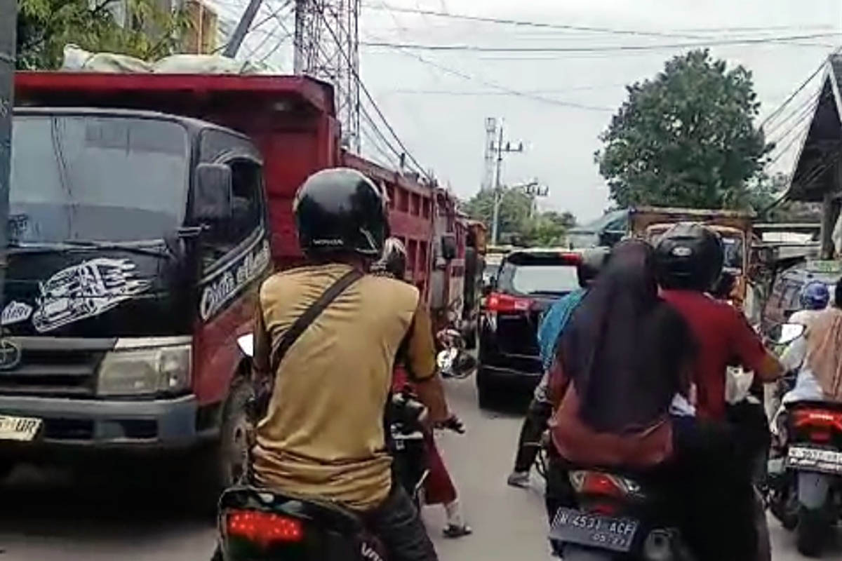 MACET: Jalan Erlangga yang macet akibat penumpukan truk material. Petugas harus turun tangan untuk mengatasi kemacetan tersebut.