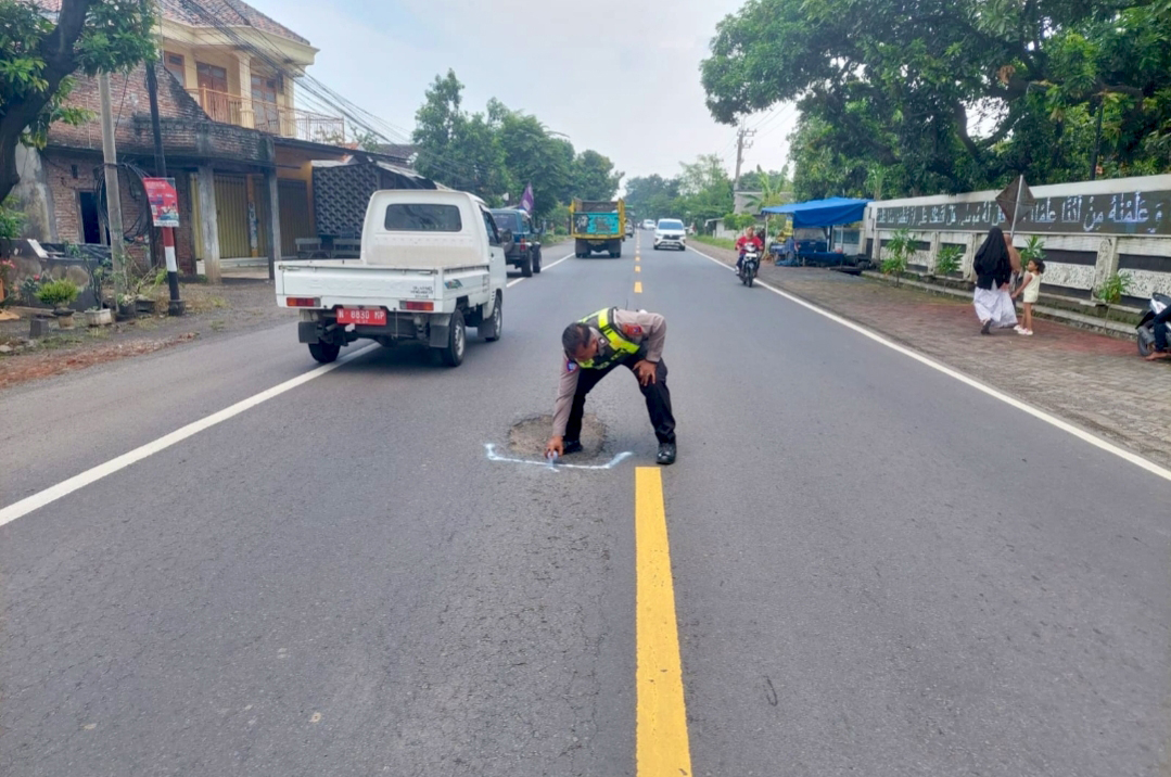 DITANDAI: Petugas Satlantas Polres Probolinggo menandai ruas jalan Pantura yang berlubang.