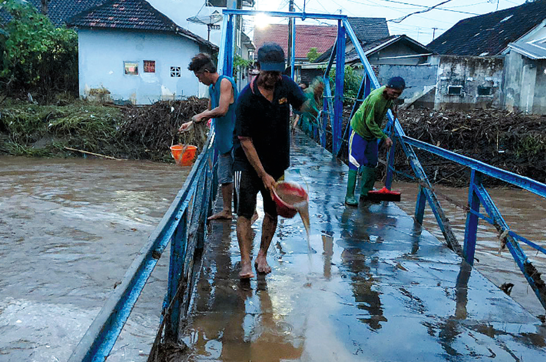 MELUAP: Sejumlah warga Desa Kedungdalem, Kecamatan Dringu, Kabupaten Probolinggo, bersih-bersih luapan Sungai Kedunggaleng, Senin (9/2) petang.