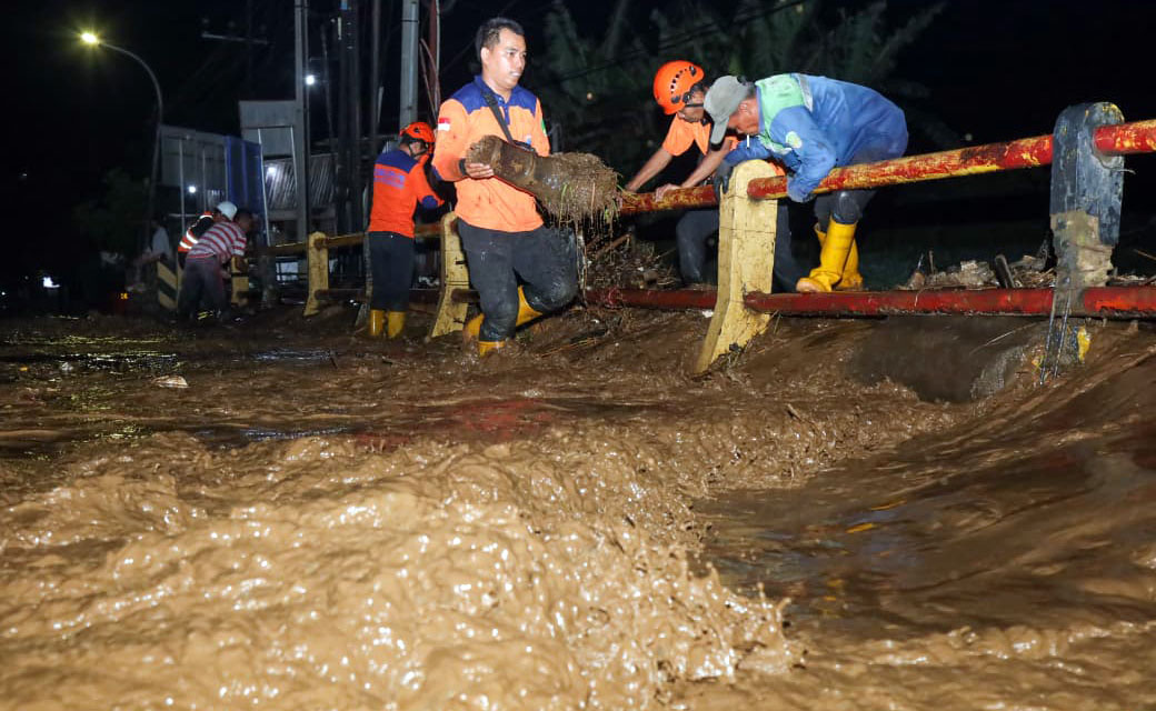 Sejumlah petugas mengevakuasi sampah yang tersangkut di jembatan Bok Wedi, Blandongan, Kota Pasuruan, Selasa malam (17/2).