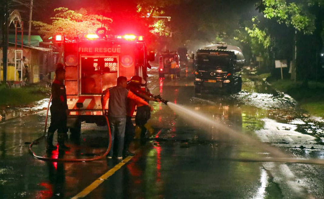 SEMPROT: Petugas BPBD Kota Pasuruan membersihkan material lumpur yang ikut terbawa banjir usai air mulai surut di jalur pantura Blandongan, Pasuruan, Selasa malam (17/2)