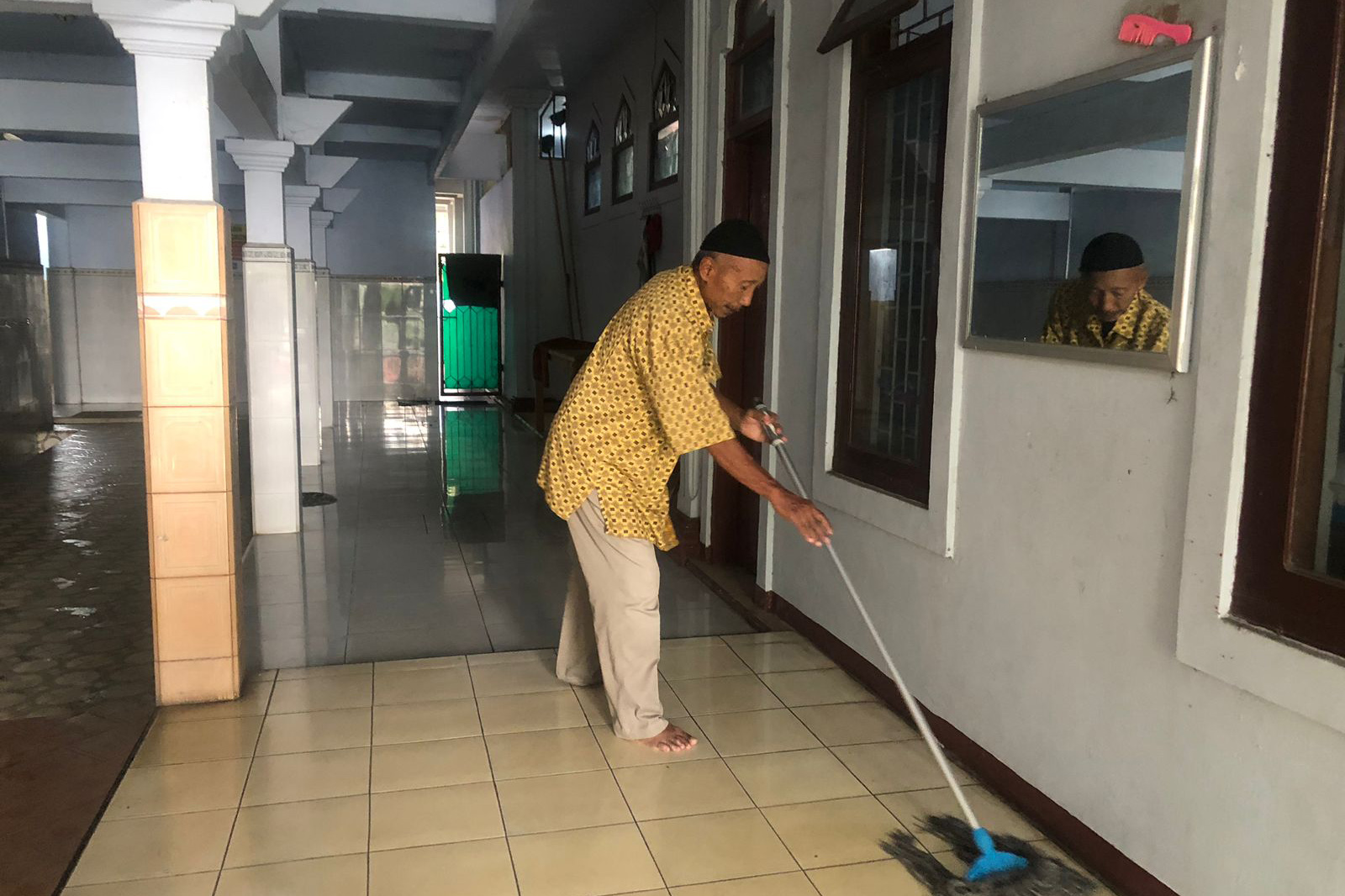 BERSIH: Djumali membersihkan lantai Masjid Al Hidayat, Kelurahan Mangunharjo, Kecamatan Mayangan.