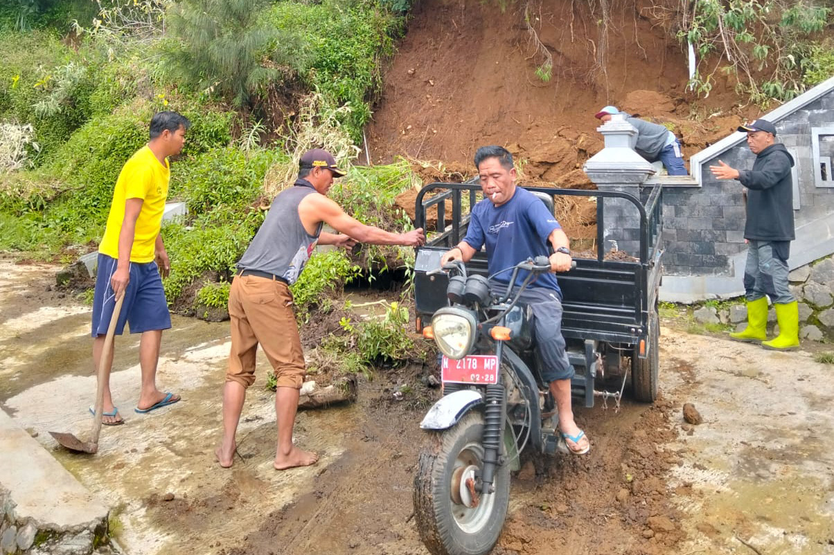 GOTONG ROYONG: Warga, pelaku usaha, dan pegawai Disporapar Kabupaten Probolinggo mengevakuasi material longsor di kaki tangga Seruni Point, Kecamatan Sukapura, Kabupaten Probolinggo, Senin (23/2).