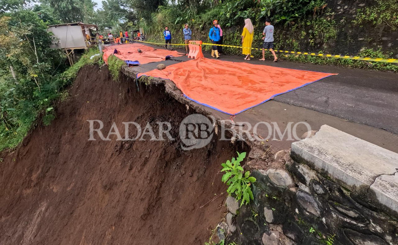 DITUTUP TERPAL: Kondisi ruas jalan kabupaten Segaran-Tiris, Kabupaten Probolinggo yang tergerus longsor. Agar tak membesar, sementara ditutup terpal. 