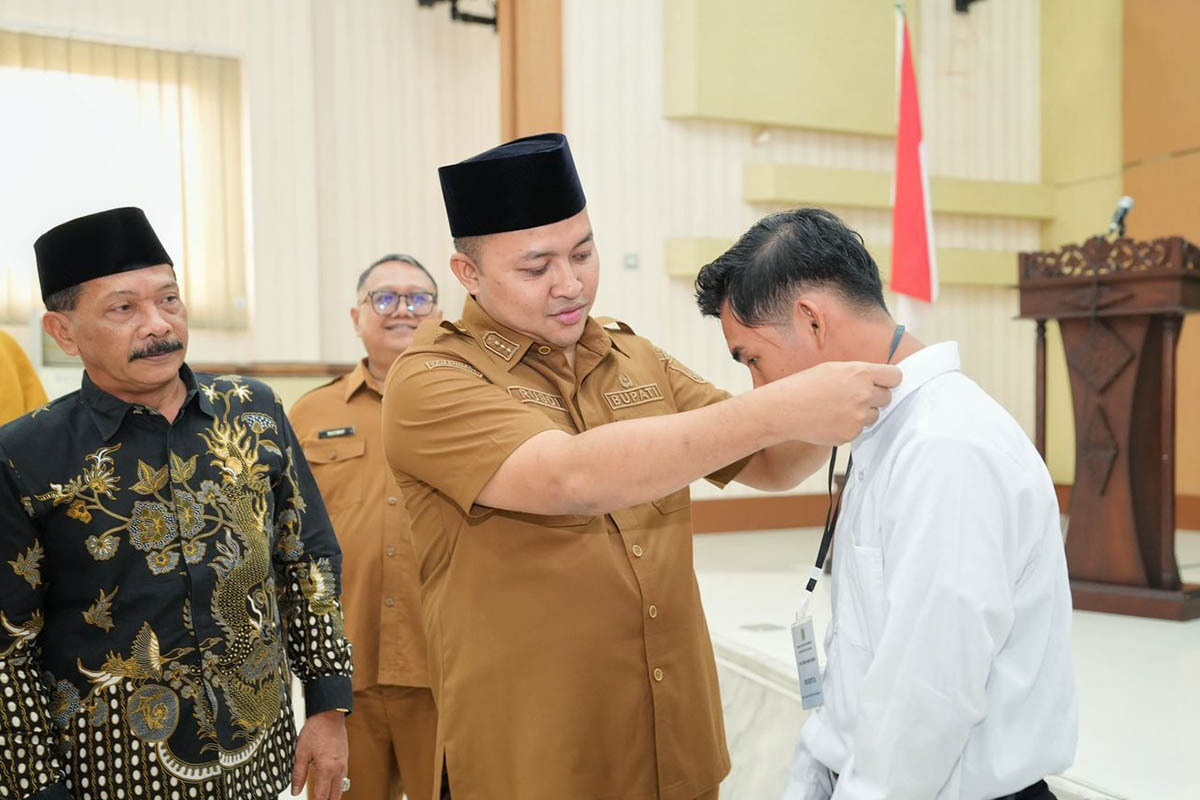 DIBIMBING: Bupati Pasuruan H.M. Rusdi Sutejo menyematkan tanda peserta terhadap peserta pelatihan kerja.