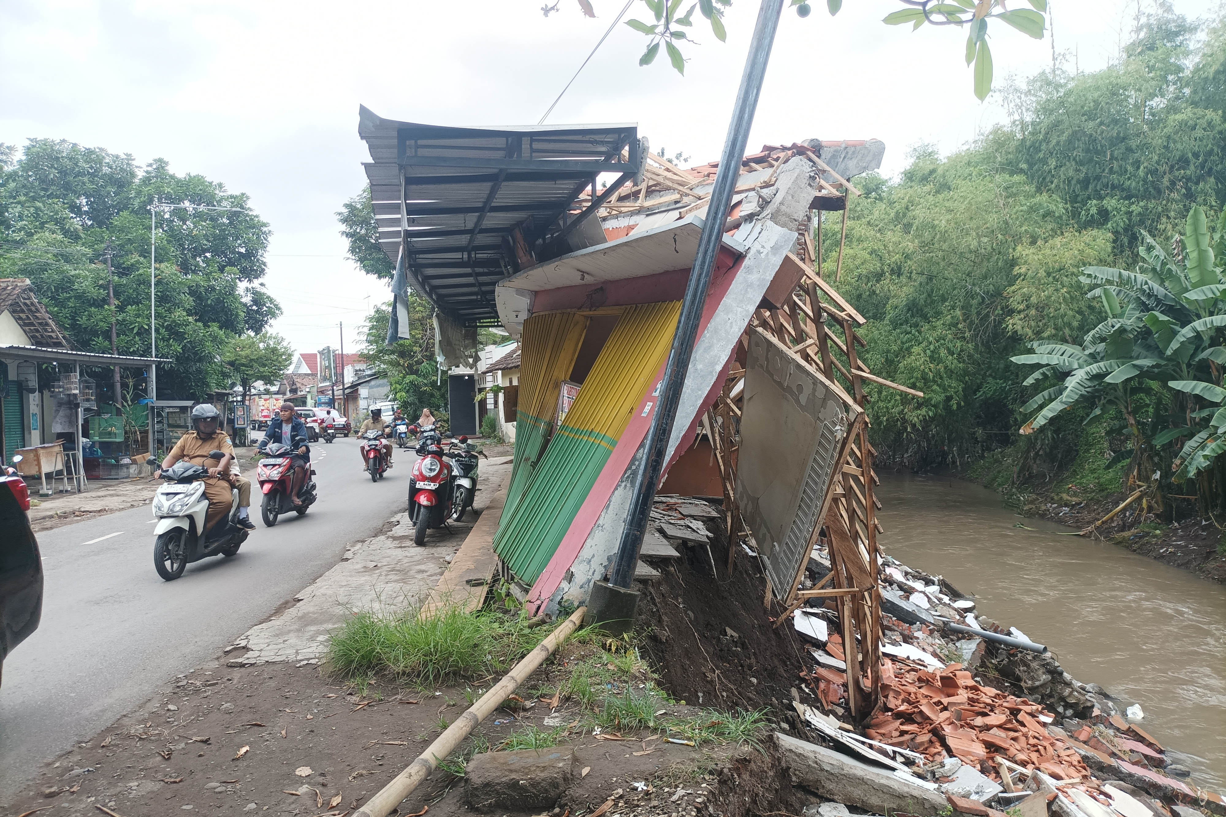 AMBRUK: Sisi selatan ruko yang berada di tepi Sungai Kertosono. Kondisinya hanya memisahkan seperempat bangunan sisanya tergerus longsor.
