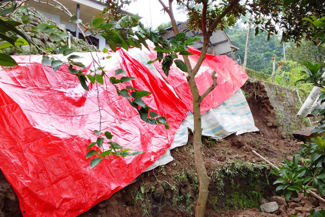 Tembok penahan tanah yang ambrol di Desa Sekarjoho, Kecamatan Prigen, hingga menutup akses tiga rumah warga. 