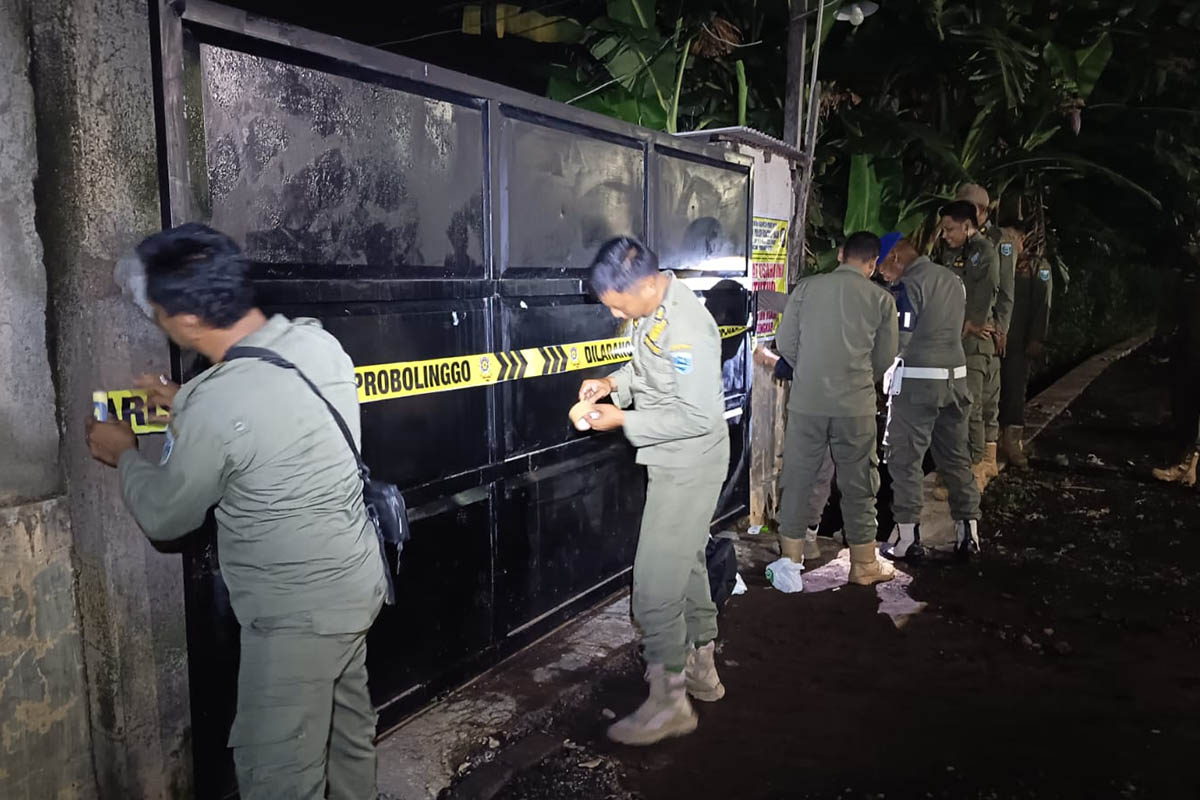 HARUS TEGAS: Personel Satpol PP memasang segel di gerbang sebuah tempat hiburan di Kecamatan Dringu, Minggu (1/3) malam. 