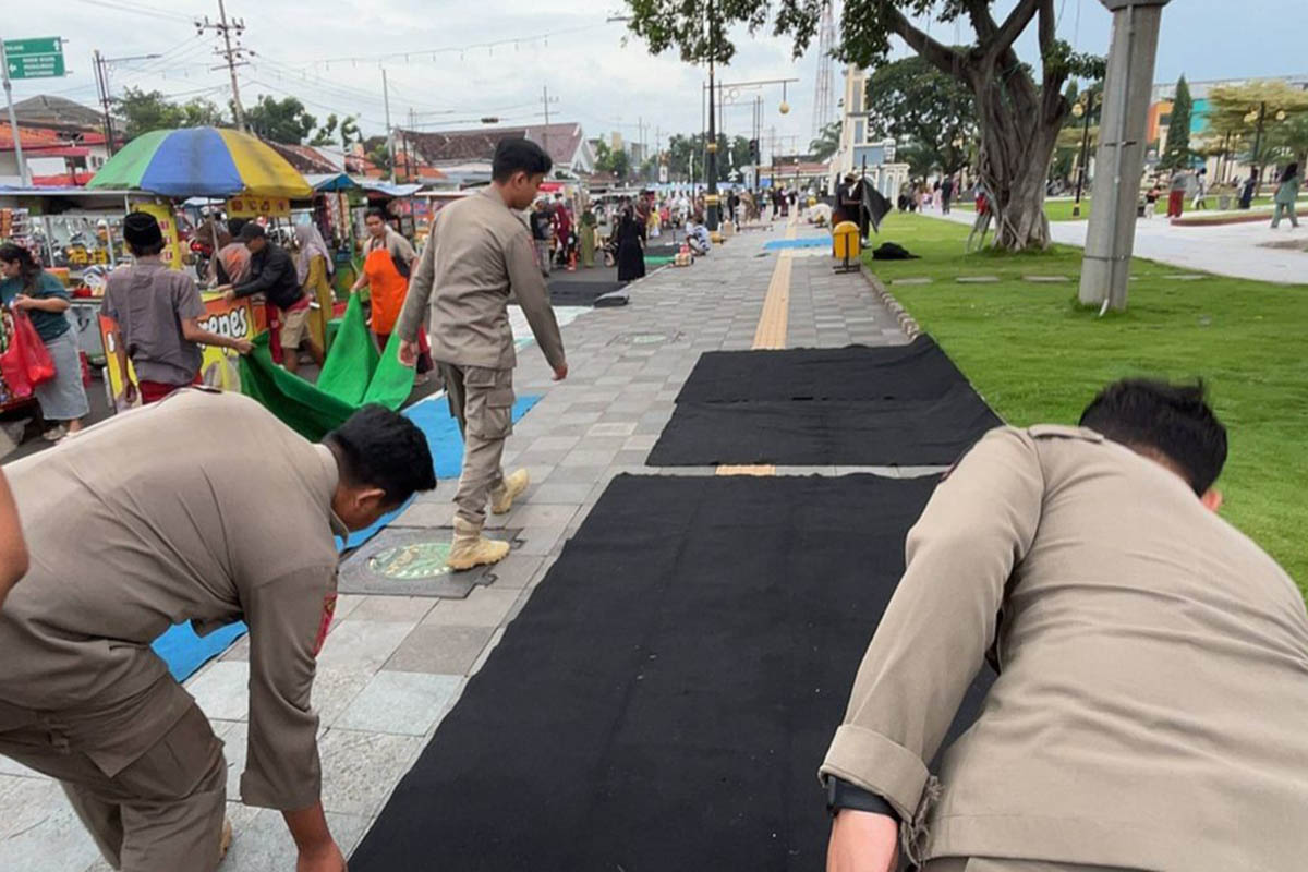 BELUM WAKTUNYA: Personel Satpol PP melipat tikar milik PKL yang dibeber di dalam Alun-alun Pasuruan