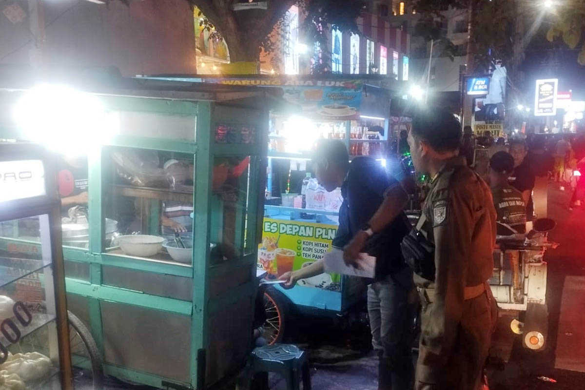 PERINGATAN: Petugas Satpol PP Kota Probolinggo saat memberikan SP3 pada sejumlah PKL di Jalan dr. Soetomo, Kota Probolinggo, Selasa (10/3) malam.