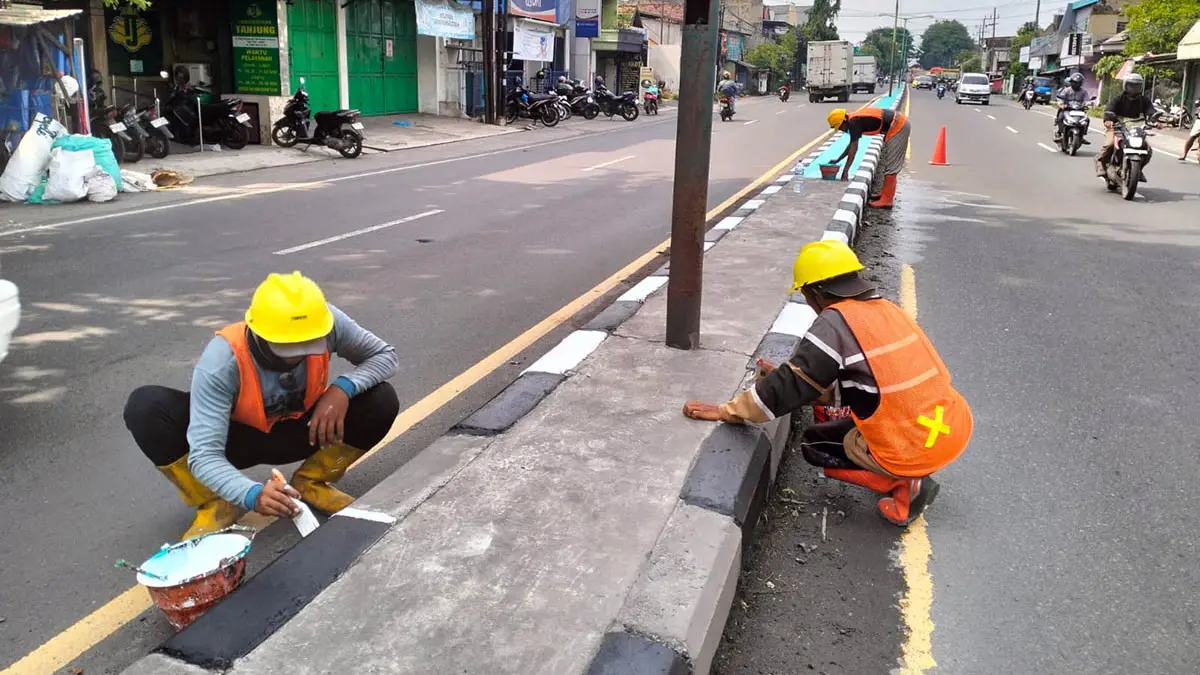 DICAT: Sejumlah pekerja tampak sibuk mengecat median jalan. Hal ini dilakukan, agar kondisi median lebih terang. (Rizal Syatori/Radar Bromo)